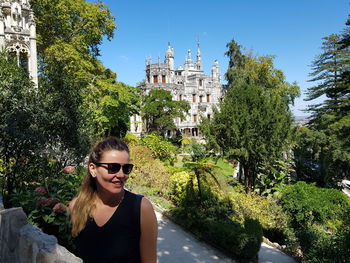 Woman wearing sunglasses sitting against trees