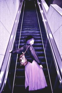 Portrait of woman standing in escalator at shopping mall