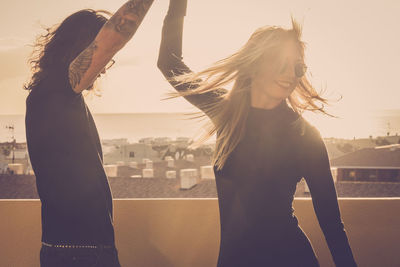 Happy friends enjoying on terrace against sky