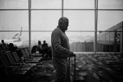 Side view of young man standing against railing