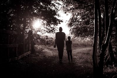 Rear view of silhouette friends standing against trees