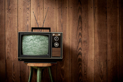 Television set on stool against wooden wall