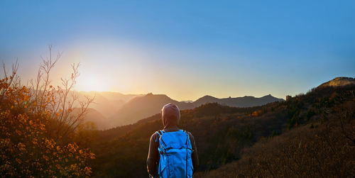 Rear view of man standing on mountain against sky