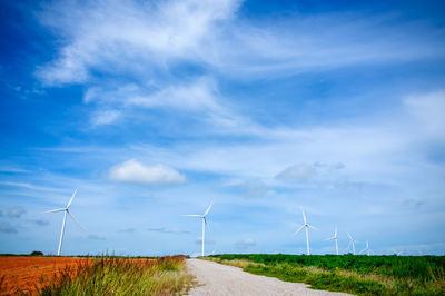 Wind turbines on field against sky