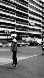 Side view full length of boy jumping on road in city