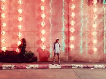 Digital composite image of man standing against illuminated wall