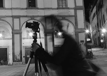 Man photographing woman in illuminated city at night