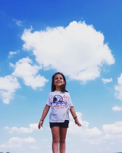 Low angle view of woman standing against blue sky