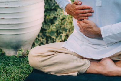 Male therapist performing reiki therapy self-treatment holding hands over his stomach