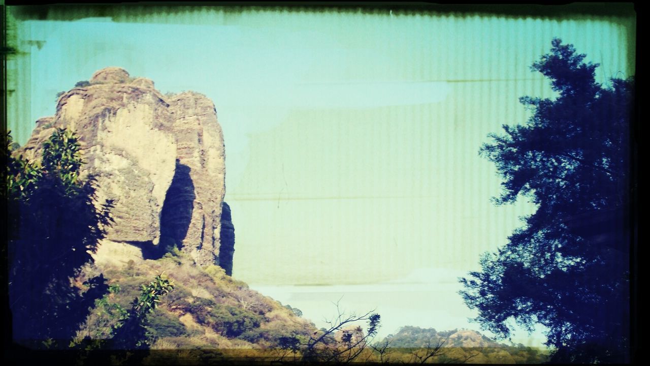 transfer print, auto post production filter, clear sky, tree, tranquility, tranquil scene, rock formation, nature, water, rock - object, scenics, beauty in nature, rock, panoramic, day, sky, outdoors, non-urban scene, cliff, no people