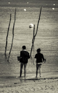 Rear view of siblings standing at beach