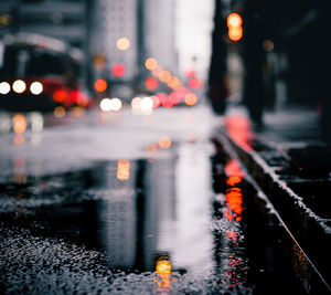 Reflection of illuminated city on wet road during rainy season