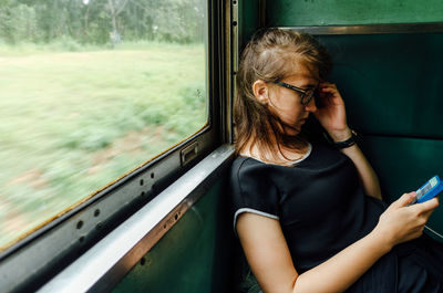 Midsection of woman looking through train window