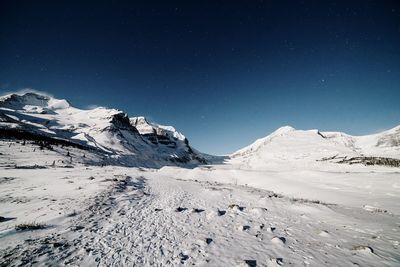 Scenic view of snowcapped mountains against sky at night