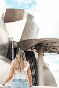 Rear view of woman standing against built structure