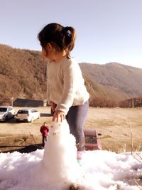 Woman standing by car on mountain against sky