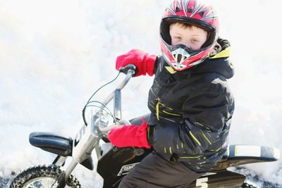 Portrait of boy riding motorcycle on snow