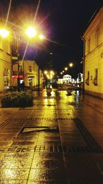 Illuminated city street against sky at night