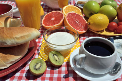 Brunch with cup of coffee, croissants, yogurt, orange juice, kiwi, orange, grapefruits and apples