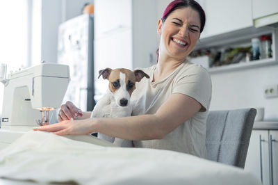 Portrait of a smiling young woman with dog at home