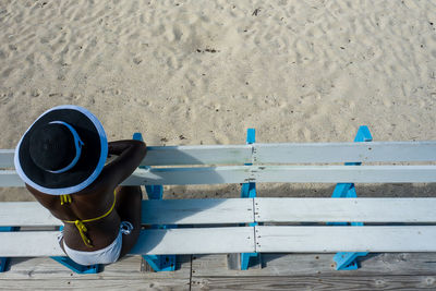 High angle view of woman sitting on bench at beach