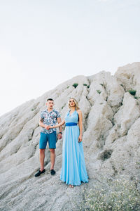 Full length of woman standing against wall against sky