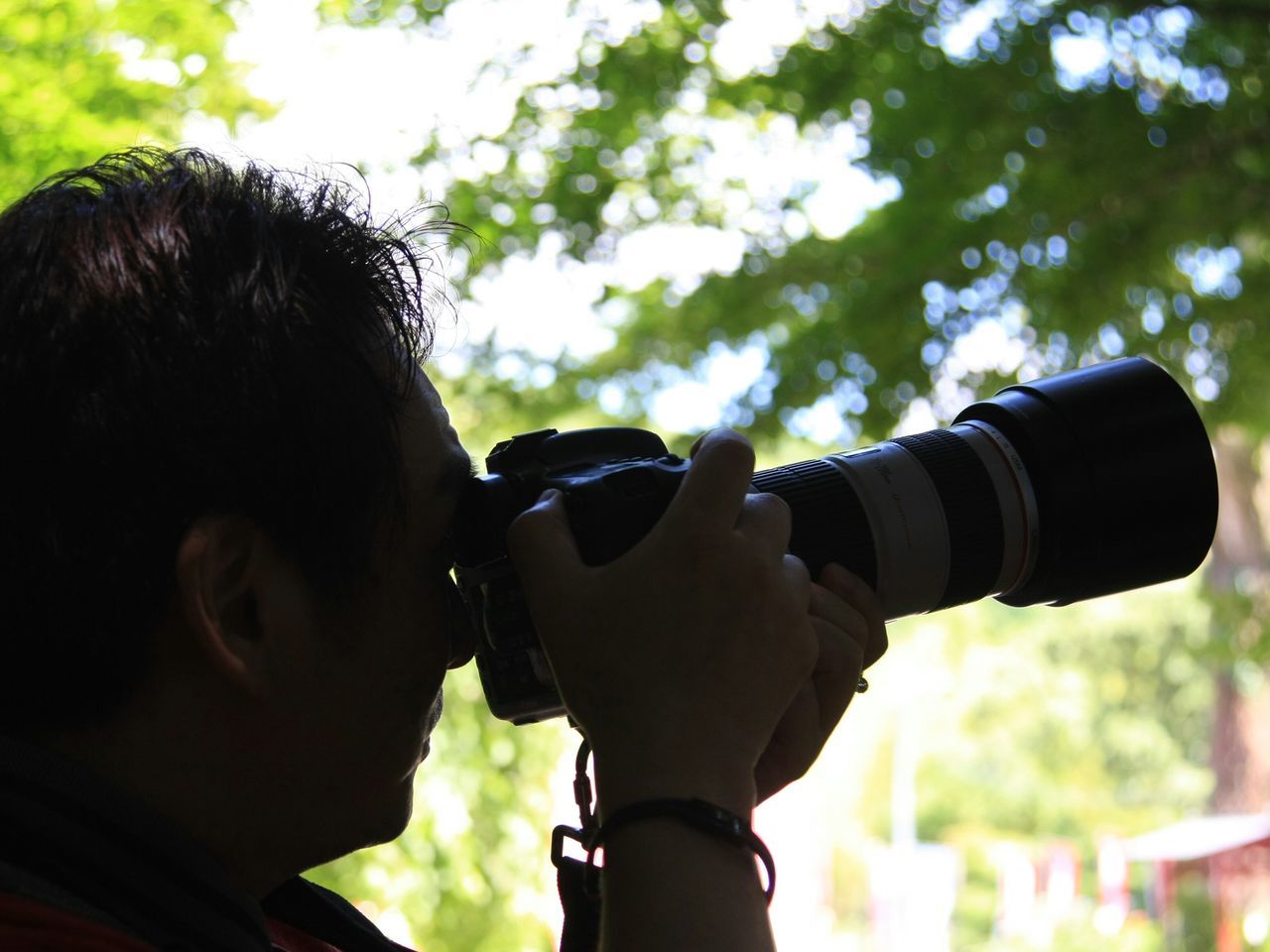 lifestyles, person, holding, focus on foreground, leisure activity, photography themes, photographing, technology, part of, men, headshot, camera - photographic equipment, close-up, cropped, digital camera, tree, sky