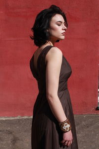 Beautiful young woman standing against red wall