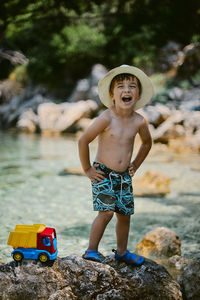 Portrait of happy boy standing on rock at beach