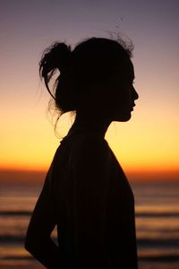 Side view of silhouette woman by sea against clear sky during sunset