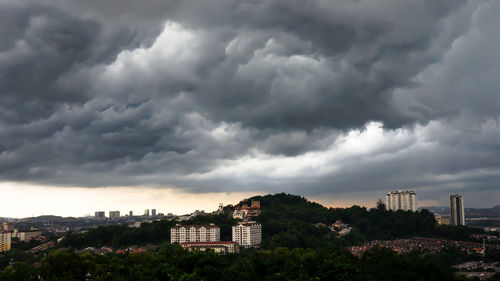 Buildings in city against dramatic sky