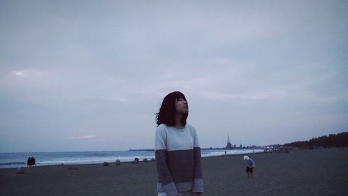 Women standing at beach against sky