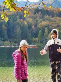 Portrait of smiling siblings standing against lake