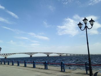 Street lights on bridge over sea against sky