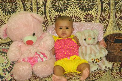 Portrait of cute baby girl sitting on bed at home