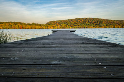 Low angle view of pier on lake by mountain against sky