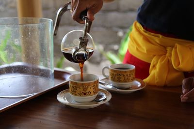 Close-up of woman pouring tea in cup