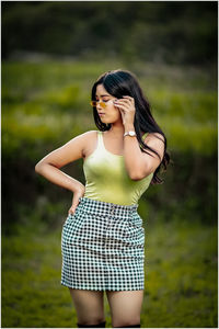 Young woman wearing sunglasses standing on field