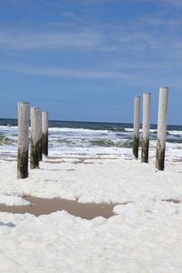 Wooden posts on beach against sky