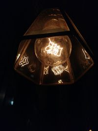 Low angle view of illuminated light bulb against black background