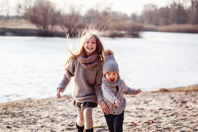 Portrait of happy girl with brother playing at lakeshore