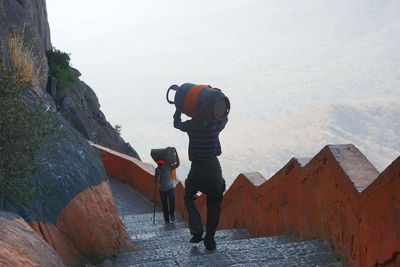 Men carrying luggage while moving on staircase against sky