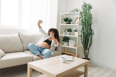 Portrait of young woman sitting on sofa at home