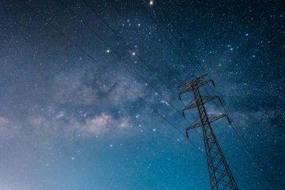 Low angle view of electricity pylon against star field