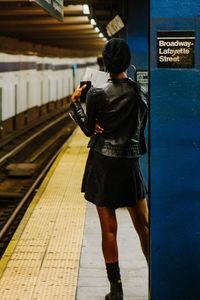 Full length rear view of woman standing at underground railroad station