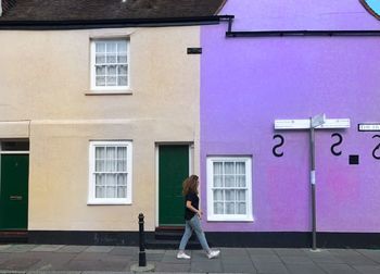 Side view of woman walking on sidewalk against building