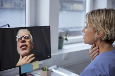 Female doctor having online consultation with senior patient