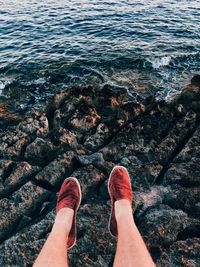 Low section of woman standing on rock by sea