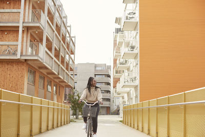 Woman standing on railing against buildings in city