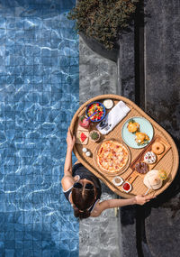 Rear view of woman standing by swimming pool